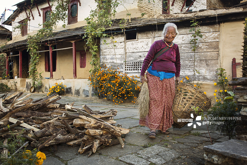 传统房屋庭院里的美丽老妇人图片素材