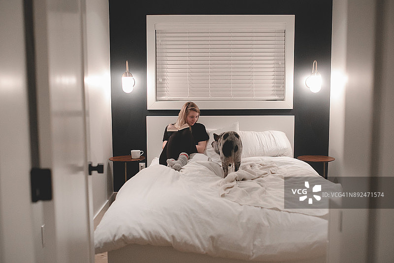 年轻女子坐在床上看着小猪佩奇图片素材