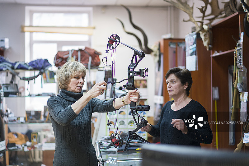 一位有魅力的金发中年妇女在狩猎商店里挑选弓箭，俄罗斯加里宁格勒，东欧图片素材