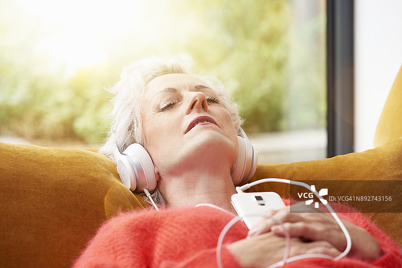 老年女性在沙发上听音乐放松图片素材