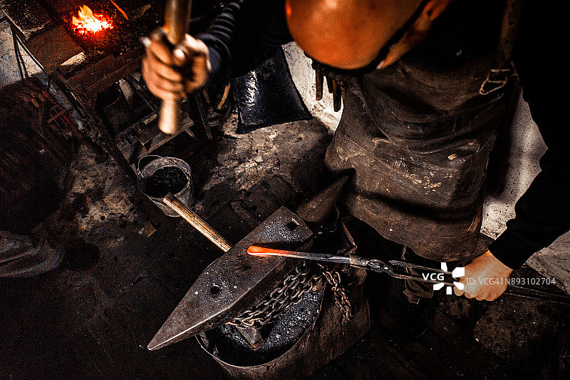 刀匠用锤子在铁砧上锻造烧红的铁块图片素材
