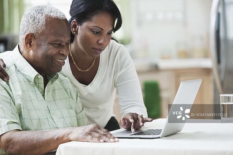 女儿帮助父亲使用电脑图片素材