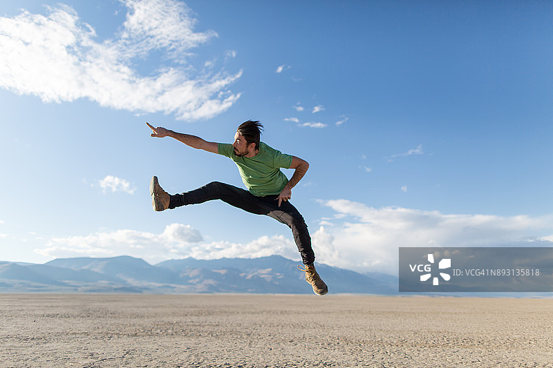年轻男子在阿尔沃德沙漠中跳踢图片素材