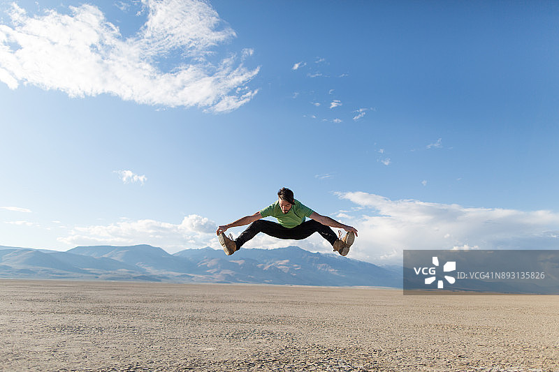 在阿尔沃德沙漠中做劈叉跳跃的年轻男子图片素材