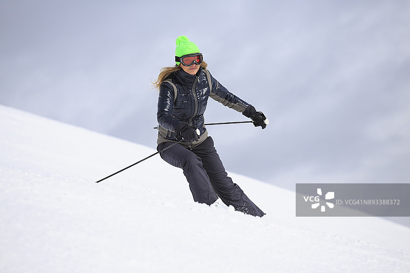 在阳光明媚的滑雪胜地滑雪的女子业余冬季运动图片素材