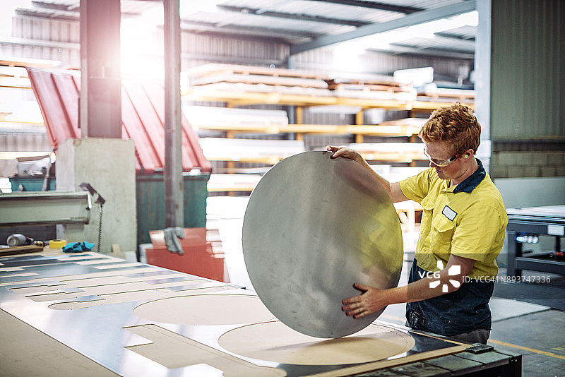 姜黄色头发的工程师正在操作金属切割机图片素材