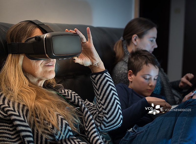 在沙发上放松的家庭，中年妇女使用VR头显图片素材