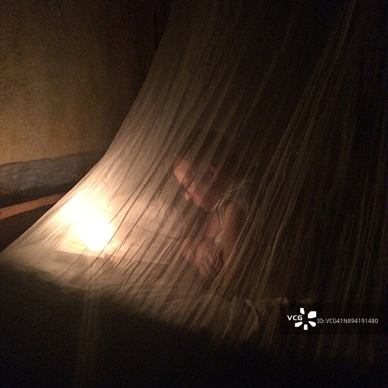 在蚊帐下用手电筒阅读图片素材