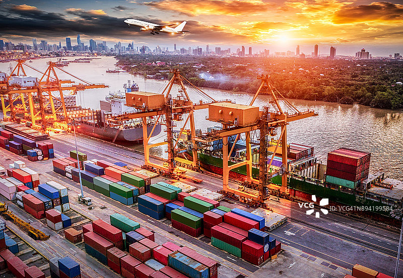 物流与运输的集装箱货轮和货机与工作起重机桥在日出船厂，物流进出口和运输行业背景图片素材