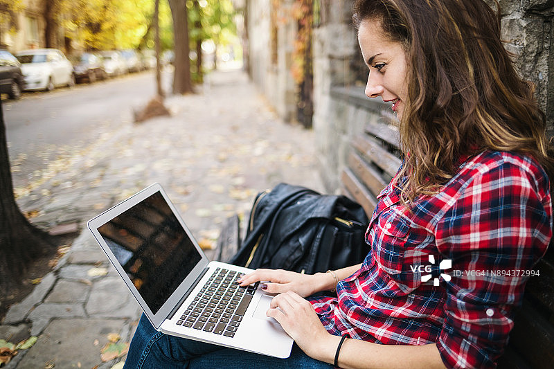 微笑的女人在笔记本电脑上浏览图片素材