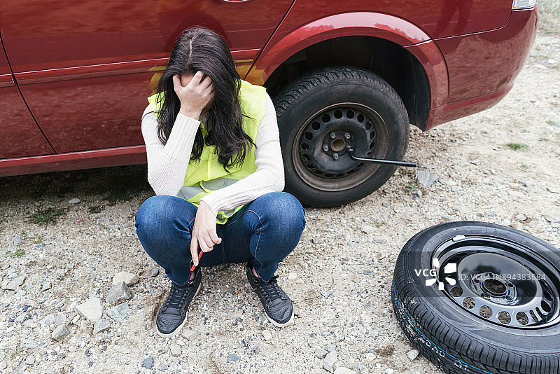 正在更换轮胎的沮丧女人图片素材