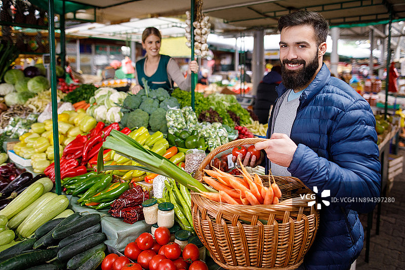 年轻男人在农贸市场摊位购买蔬菜图片素材