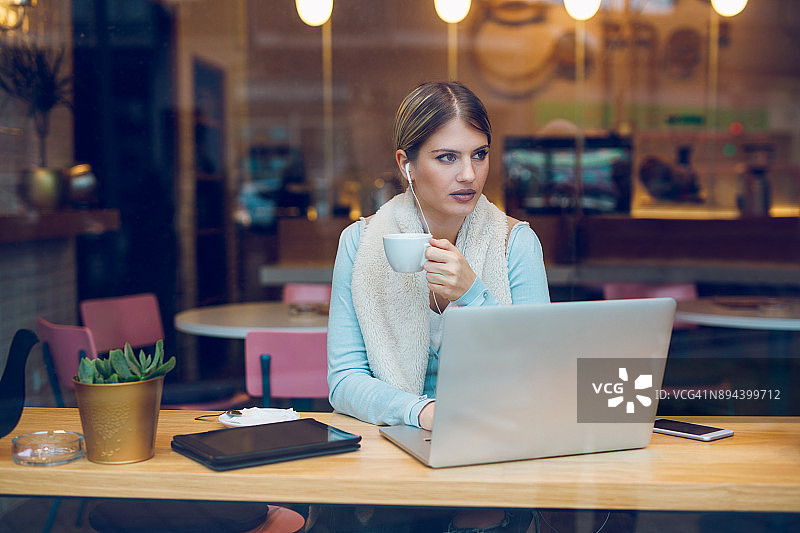 在咖啡馆用笔记本电脑打字的时尚博主图片素材