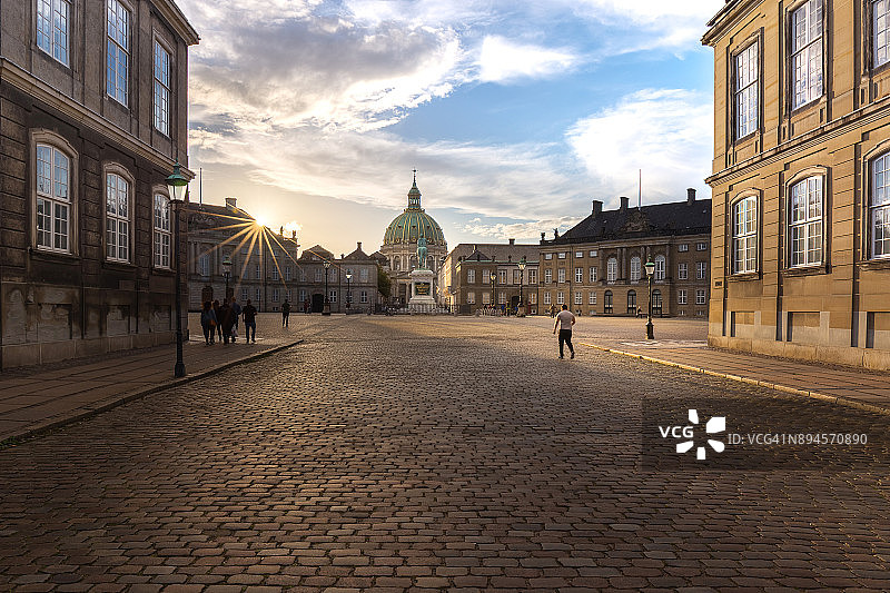 日落时分，走进丹麦哥本哈根阿美琳堡宫的游客图片素材