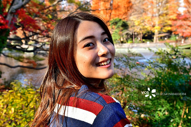 在东京井之头公园秋色中摆姿势/跳跃的年轻日本女子图片素材