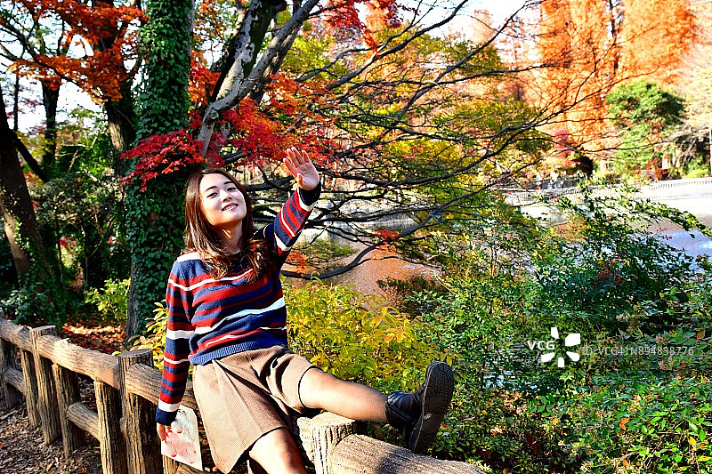 在东京井之头公园秋色中摆姿势/跳跃的年轻日本女子图片素材
