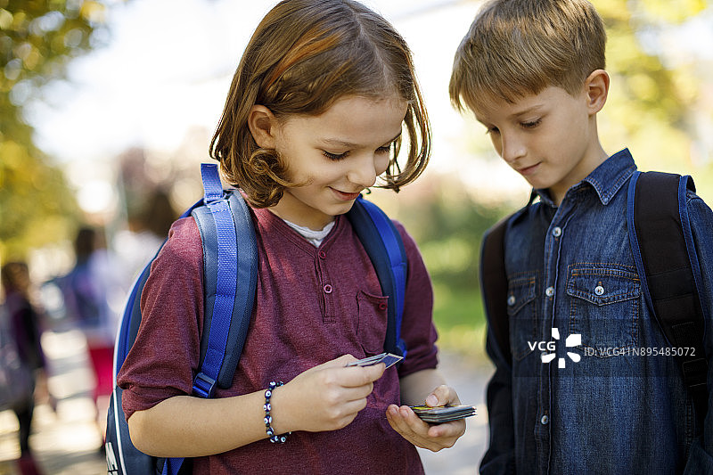 在校园里玩纸牌的可爱小男孩们图片素材