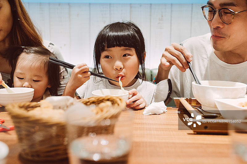 可爱的小女孩和家人一起快乐地吃面条图片素材