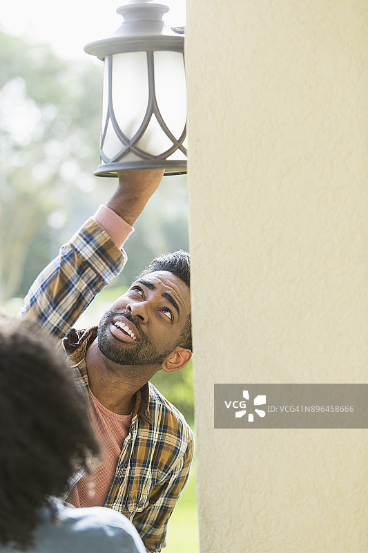 情侣在房子外面更换灯泡图片素材