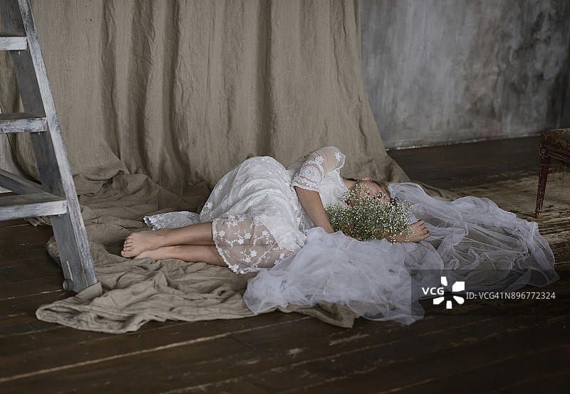 穿着白色连衣裙，手捧鲜花的年轻女孩的梦想图片素材