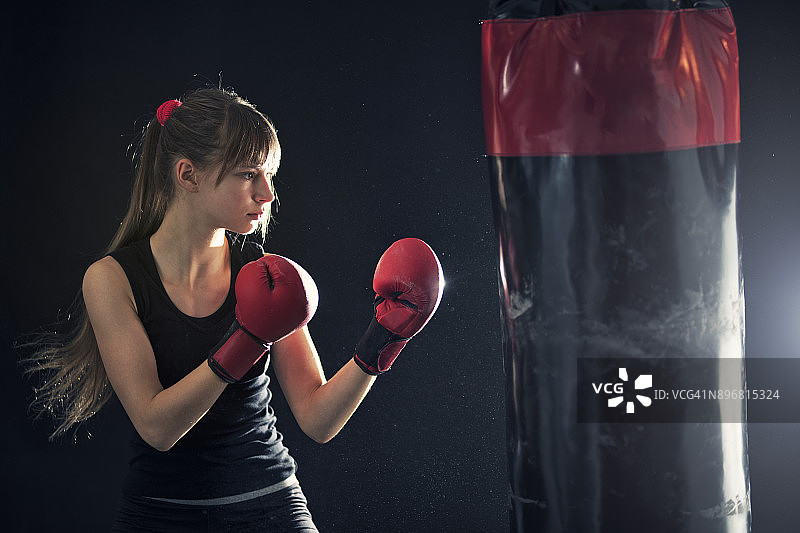 用拳击袋进行拳击训练的少女图片素材