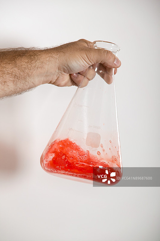 手摇动装满液体的烧瓶图片素材