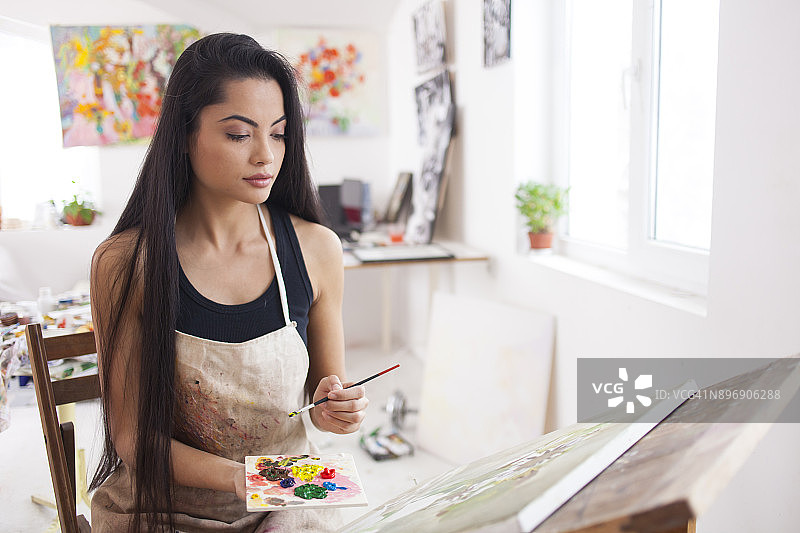 美丽的年轻艺术家在工作室里绘画图片素材