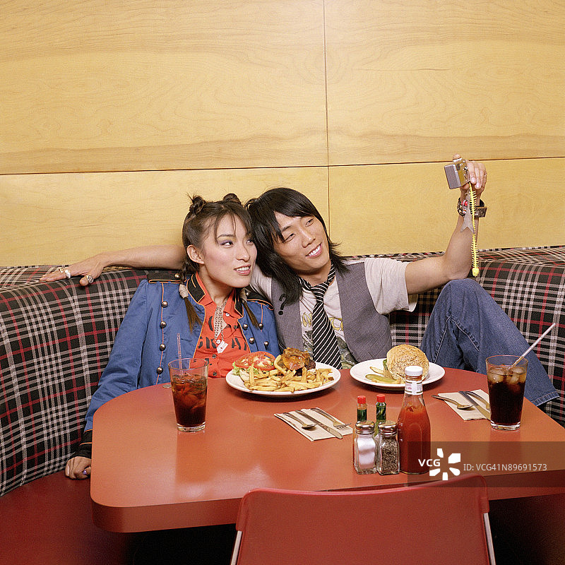 在小餐馆里用相机拍摄的情侣图片素材