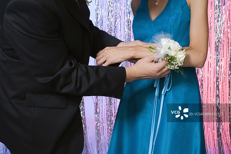 男孩帮助女孩佩戴舞会手腕花图片素材
