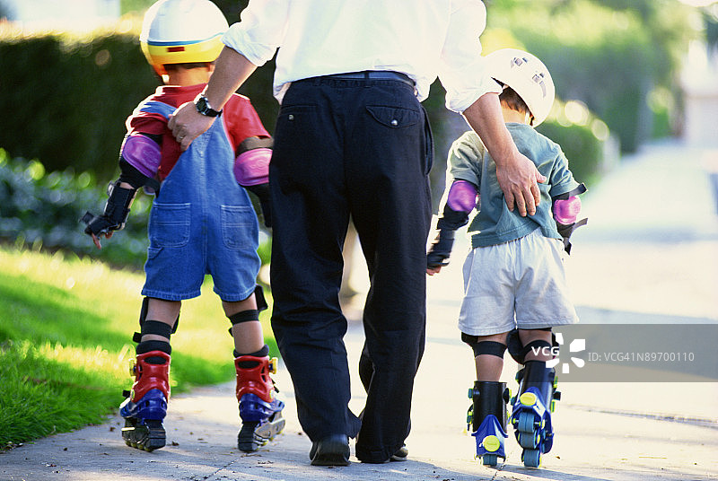 父亲帮助儿子们玩轮滑图片素材