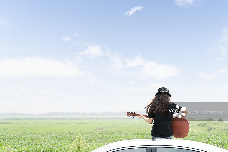 天空下时尚女孩车顶弹吉他图片素材