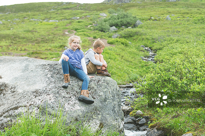 两个孩子在小溪边的巨石上摔跤玩耍图片素材
