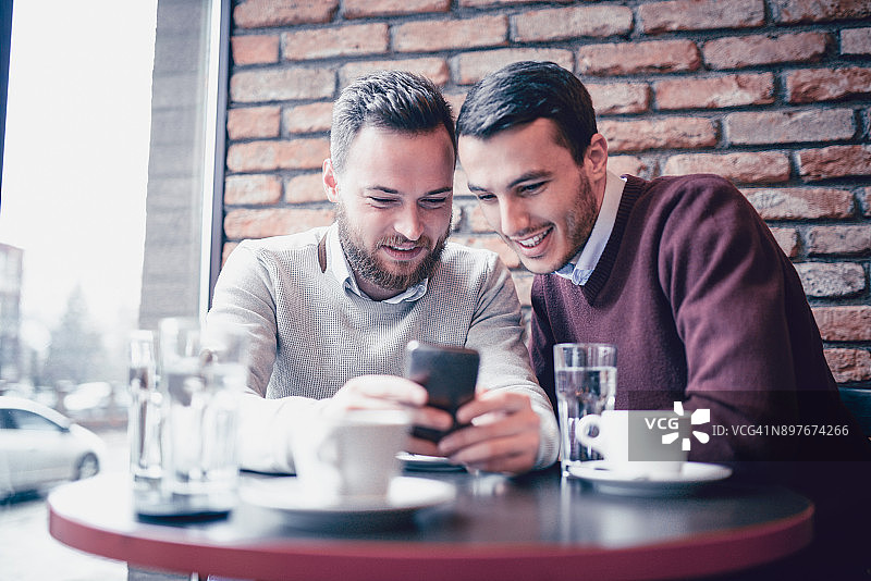 咖啡馆里看智能手机的两位男商人图片素材