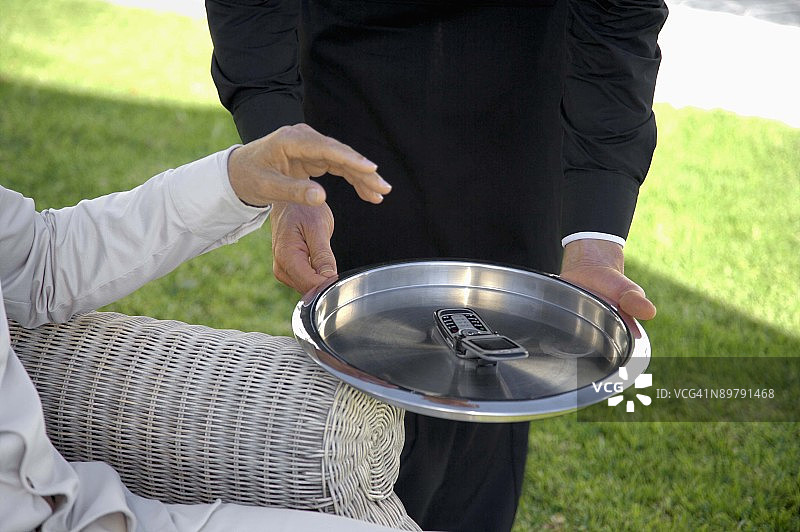 托盘上放着手机的管家图片素材