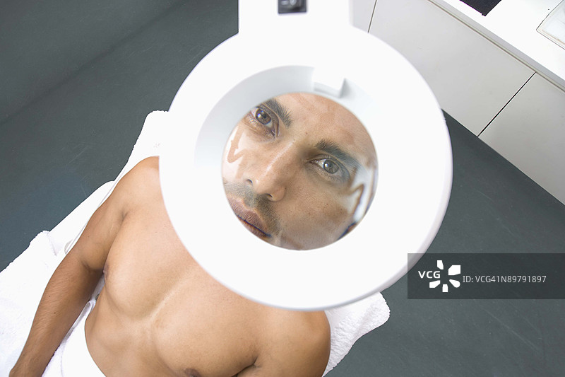 水疗中心下的放大镜灯下的男人图片素材