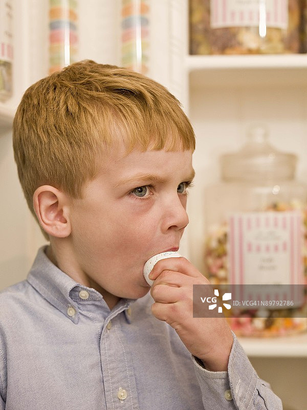 男孩在糖果店吃硬糖图片素材