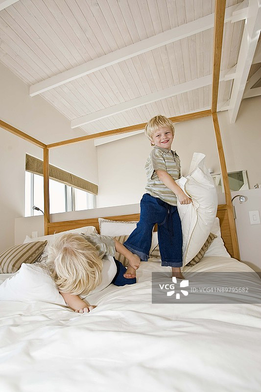 双胞胎男孩在床上枕头大战图片素材