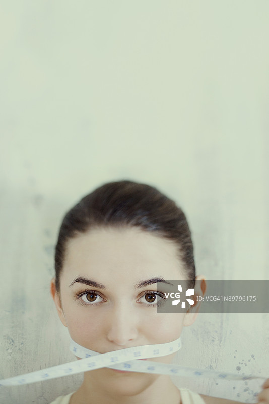 用卷尺缠绕嘴巴的女人图片素材