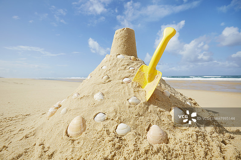 法国海滩上带有贝壳和黄色沙铲的沙堡图片素材