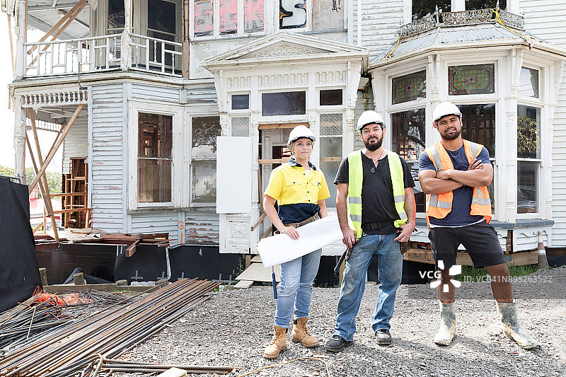 正在翻新的老房子前的建筑工人图片素材