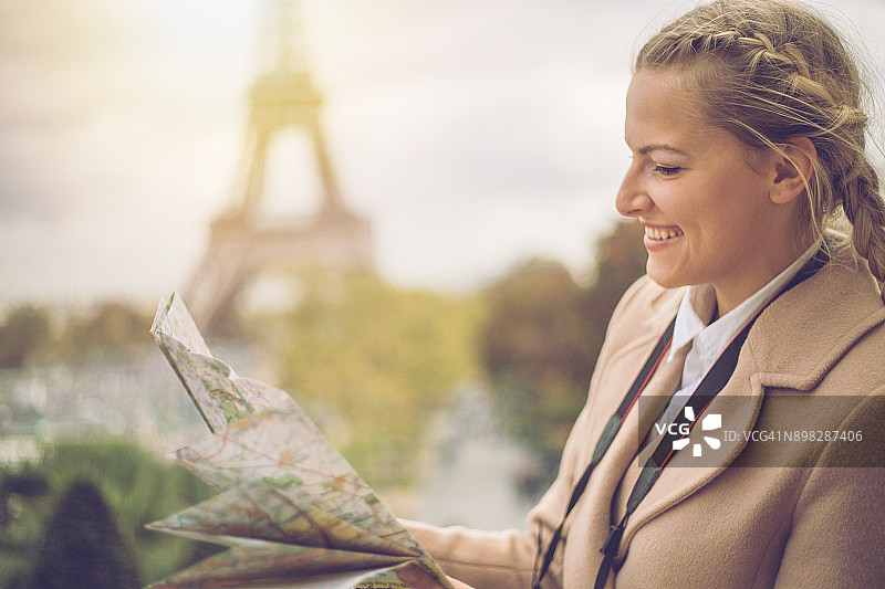 快乐的金发女孩在巴黎旅游，手持埃菲尔铁塔街道地图图片素材