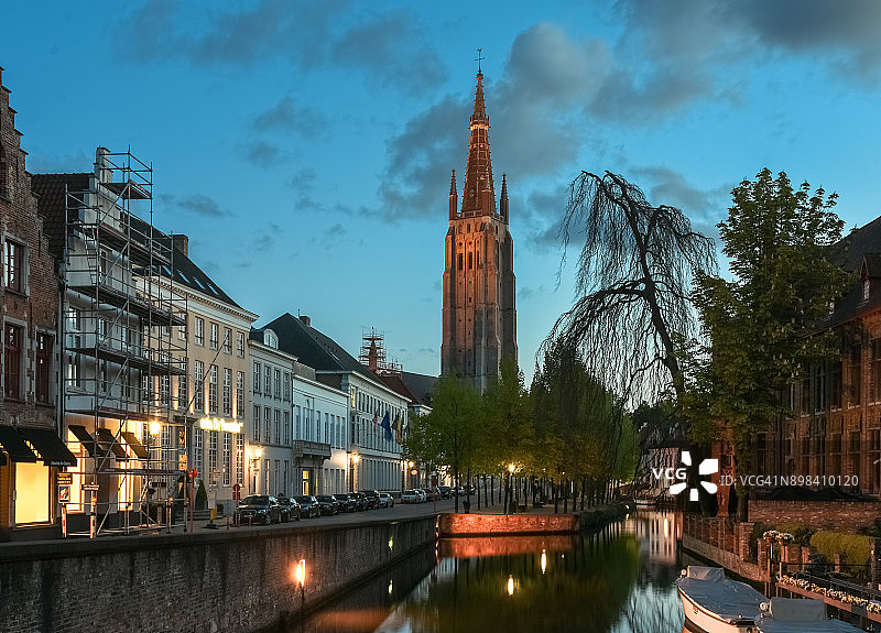 傍晚时分被照亮的布鲁日迪弗运河，背景是中世纪的圣母教堂砖砌钟楼，比利时图片素材