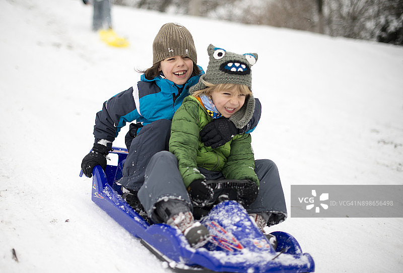 兄弟俩在罗马尼亚特兰西瓦尼亚布拉索夫的冬季森林里玩雪橇图片素材