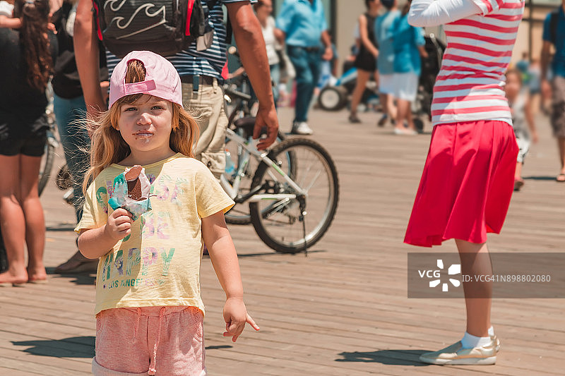 小女孩在地中海长廊的人群中吃冰淇淋图片素材