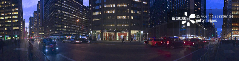 黄昏时分，人们在人行道上行走，第六大道上灯火通明的办公楼、汽车和出租车全景图片素材