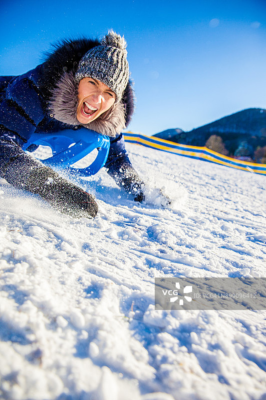 快乐的女人乘坐雪橇下山图片素材