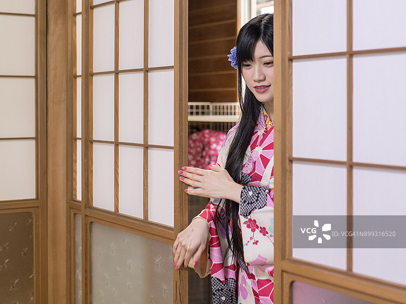 年轻女子身穿和服打开日式推拉门图片素材