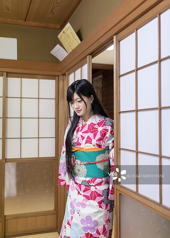 身穿和服进入日式榻榻米房间的年轻女人图片素材