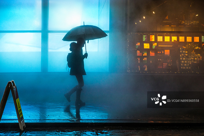 在下曼哈顿雾蒙蒙的市中心，一位女人在黑暗中雨中行走图片素材