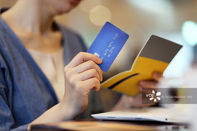 在咖啡馆里拿着信用卡和银行存折的女人图片素材